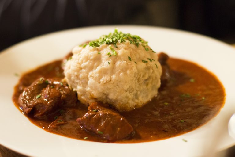 Traditional goulash with a bread dumpling served on a white plate