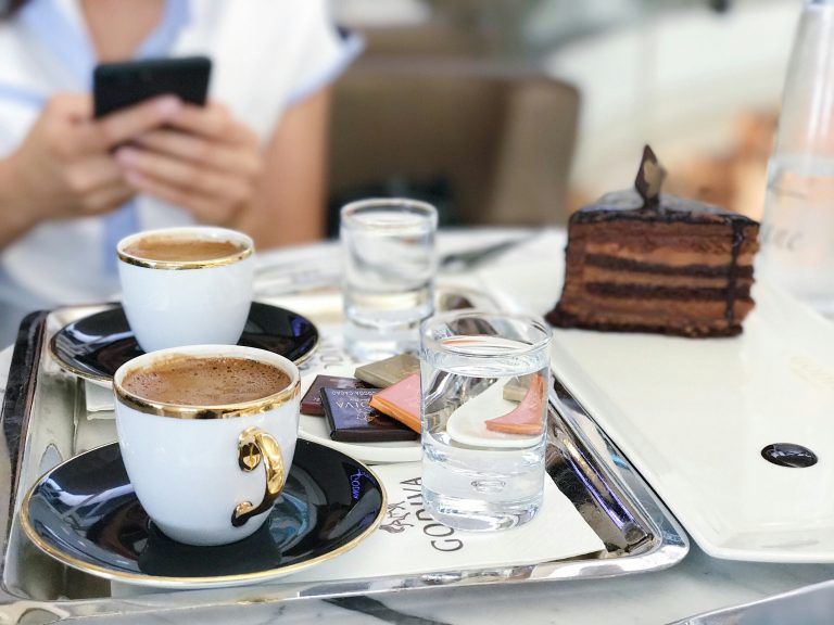 Coffee cups on a tray, two glasses of water and a slice of Sachertorte