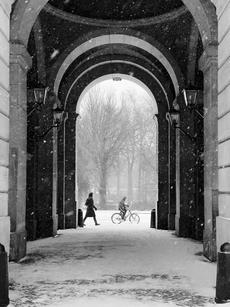 Amsterdam Light Festival 2024 - a person walking and one riding a bike under the snow
