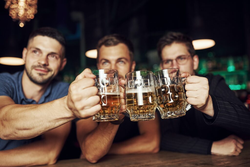 Junggesellenabschied in Amsterdam - drei Männer stoßen mit Bieren an