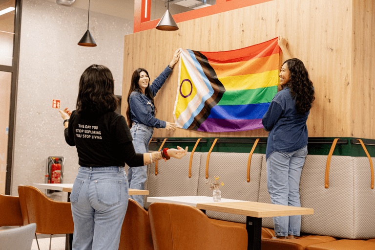 Meet our Explorers - two women holding a LGBTQIA+ flag and a woman looking at it
