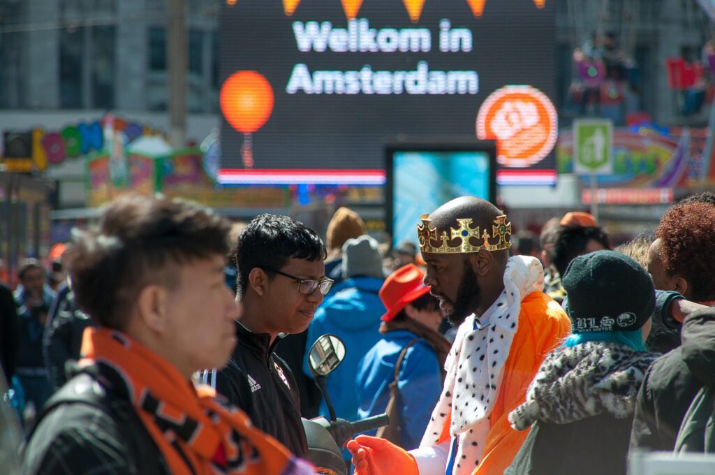 Best Festivals in Amsterdam 2024 - a person dressed in orange with a crown and other people celebrating King's day in Amsterdam