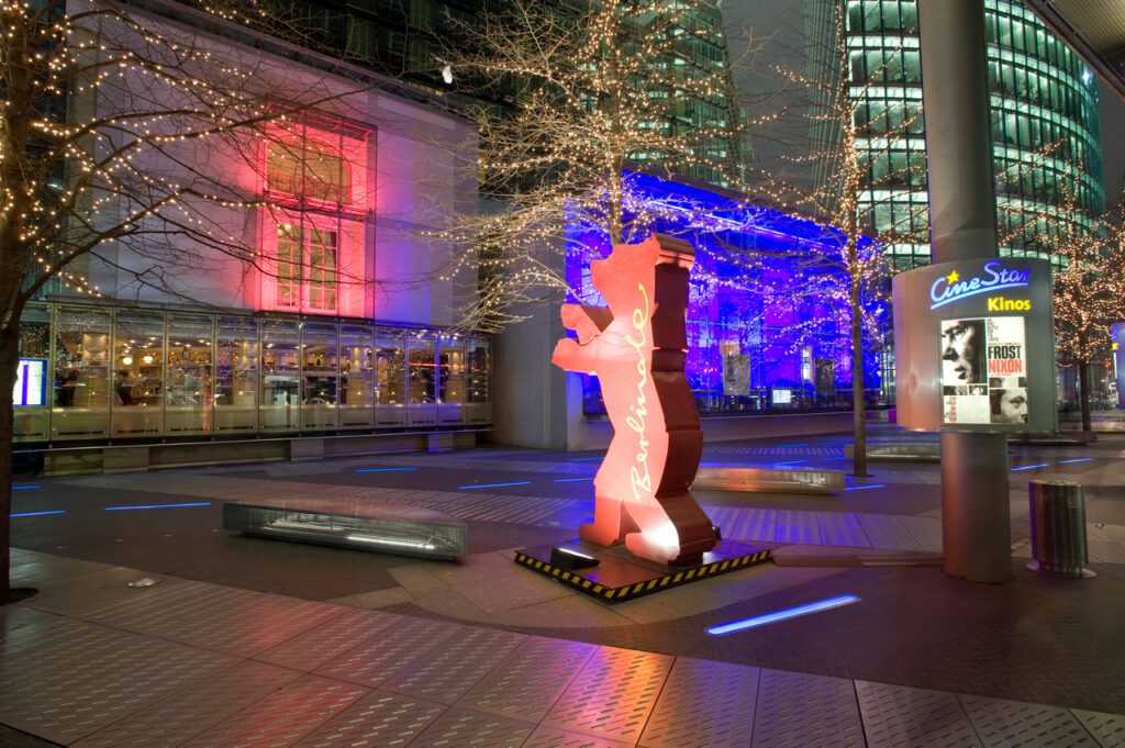 Berlinale Filmfestival 2024 - eine Bärenstatue, Maskottchen der Berlinale, zwischen Gebäuden in der Nacht