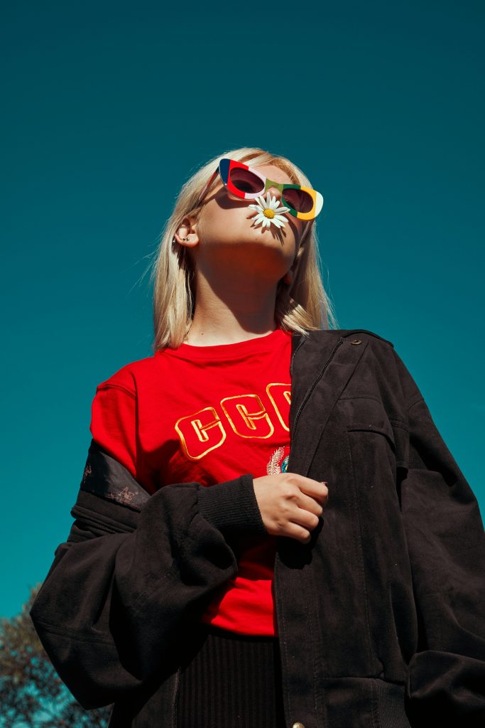 Shopping in Berlin: ein Mädchen mit Sonnenbrille, rotem T-Shirt und schwarzer Jacke.