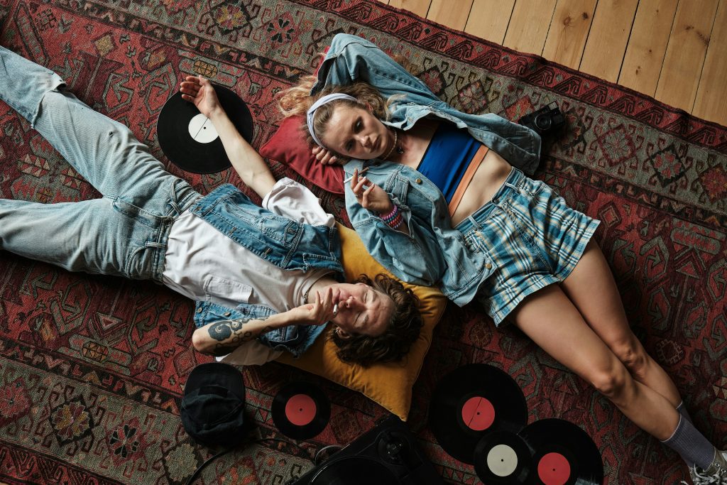 Second hand Hamburg: ein Paar in Vintage-Kleidung liegt auf einem Teppich mit Schallplatten  