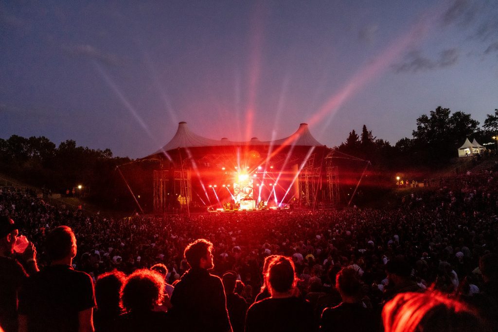 Konzerte in Berlin 2024: Parkbühne Wuhlheide bei Nacht, das Publikum wird von den roten Lichtern der Bühne getroffen