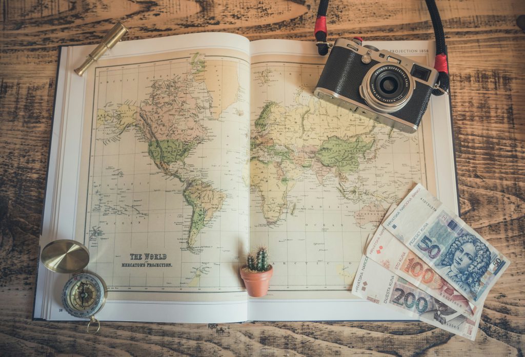 Vintage shops Munich: an old map on the table along with a vintage camera, banknotes, a cactus magnet and a compass