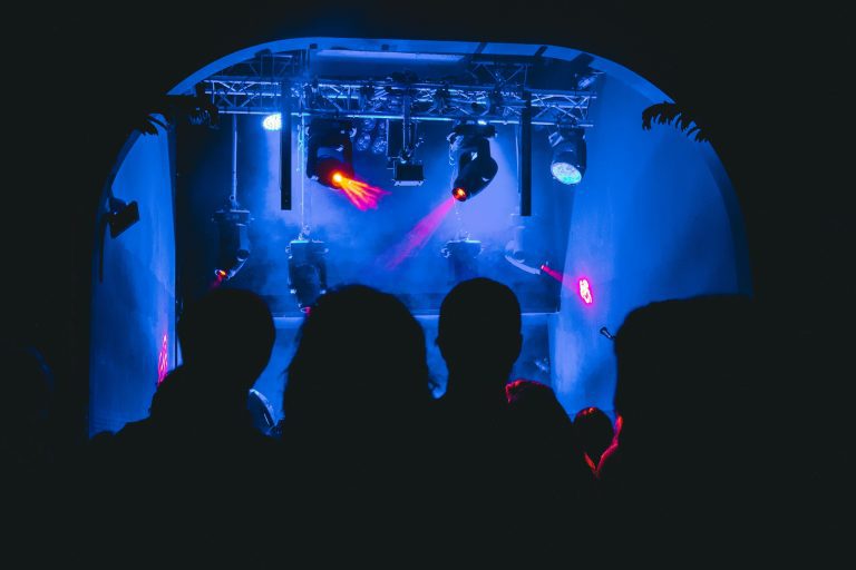 Silhouettes of a crowd at a nightclub with vibrant blue and red stage lighting