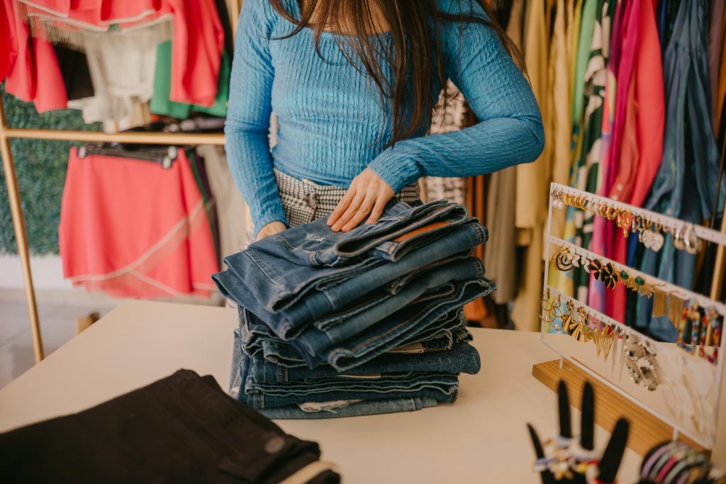 Second-Hand Läden Berlin: eine Frau hält einen Stapel Jeans in einem Laden