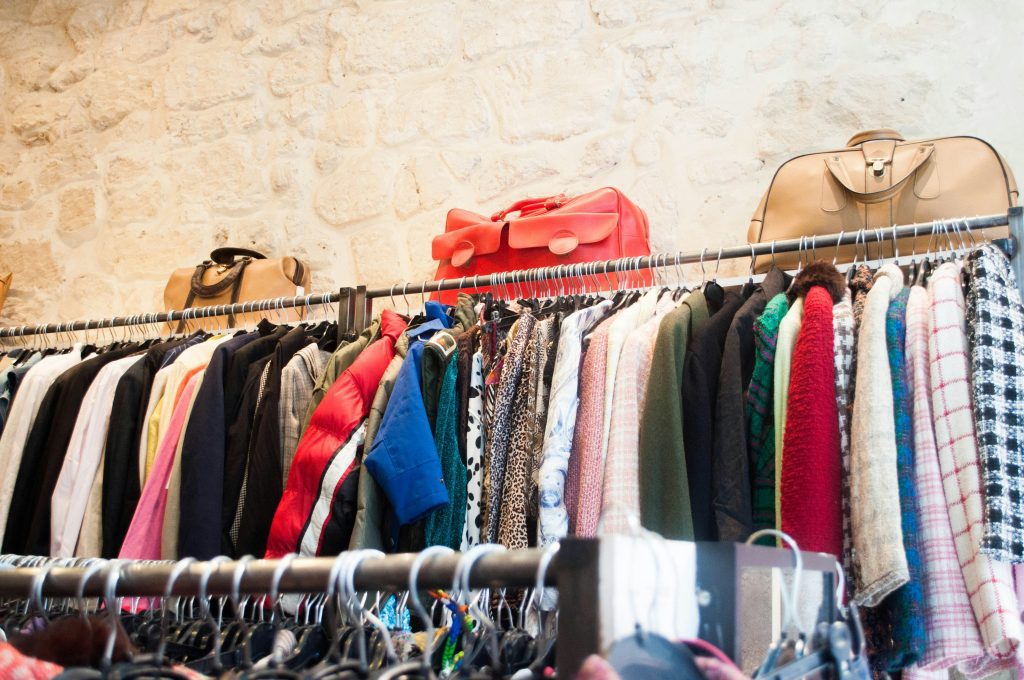 Second-Hand Läden Berlin: ein Kleiderständer mit Vintage-Kleidung und Taschen obendrauf