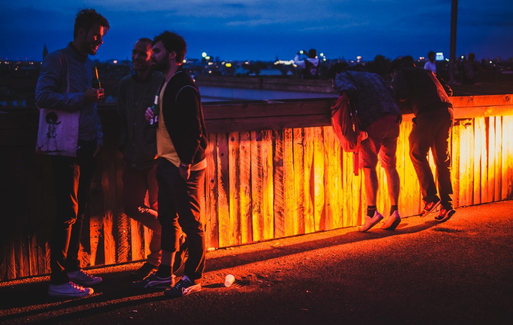 Cool bars in Berlin: bar goers looking at the panorama from the Klunkerkranich rooftop