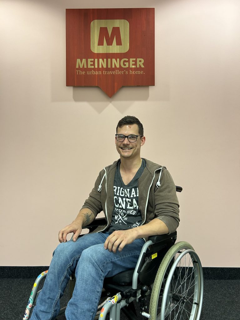 Nico Schmiedtke portrait in front of the MEININGER Hotels logo