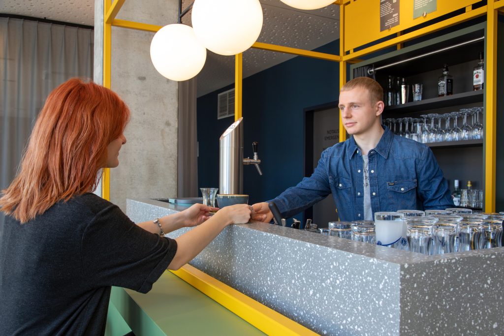 Lerne unsere M-Explorers kennen: Johannes Schwarz serviert einen Kaffee an der Bar des MEININGER Bremen Hauptbahnhof