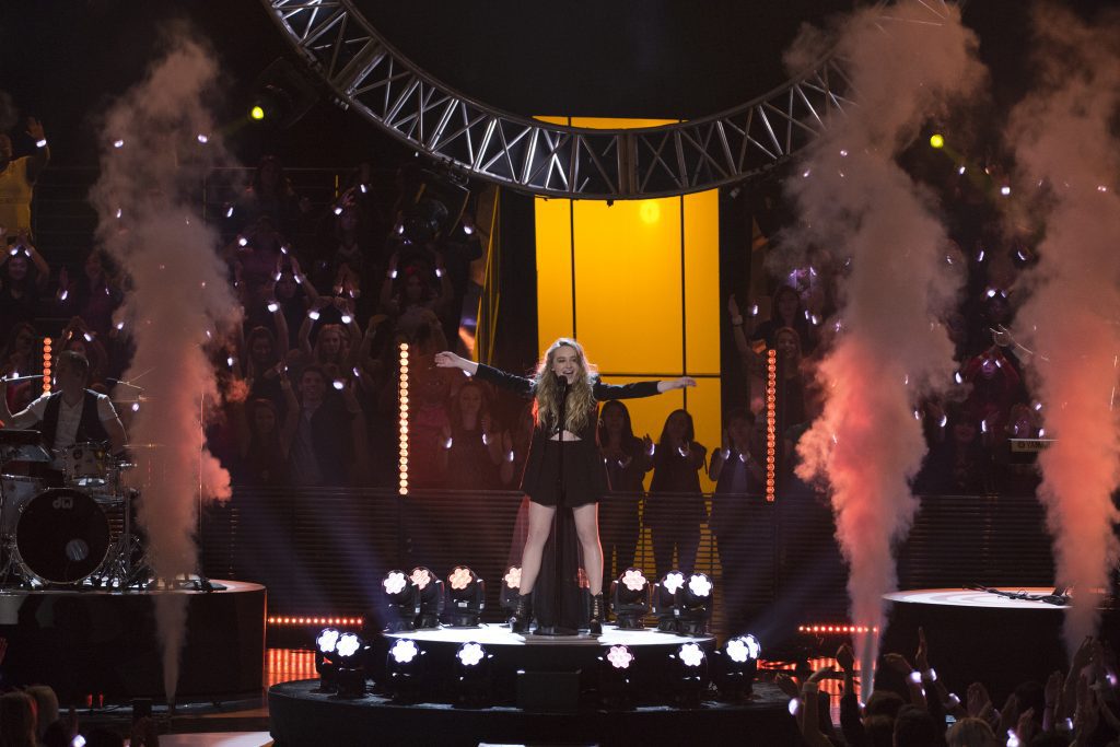 Sabrina Carpenter tour Europe: Sabrina Carpenter performing on stage with dramatic lighting and smoke effects, surrounded by an energetic crowd