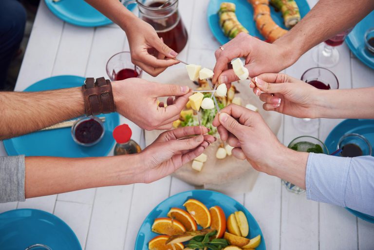 Friends enjoying cheese fondue together at a vibrant table with fresh appetizers