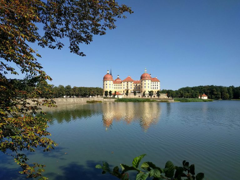 Baroque Moritzburg Castle reflecting on a lake, surrounded by lush greenery