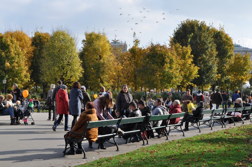 Bank holidays in Austria: People gathering in a park with autumn foliage, celebrating Austria’s National Day with festive activities and socializing