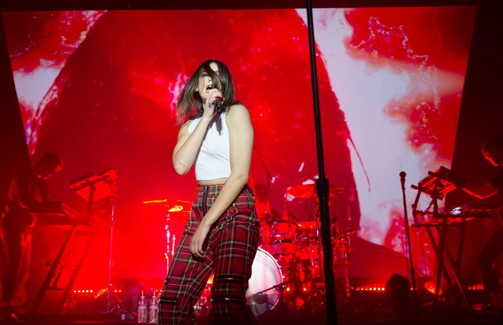 Concerts in Paris: Dua Lipa performing on stage in plaid pants with a vibrant red light display behind her