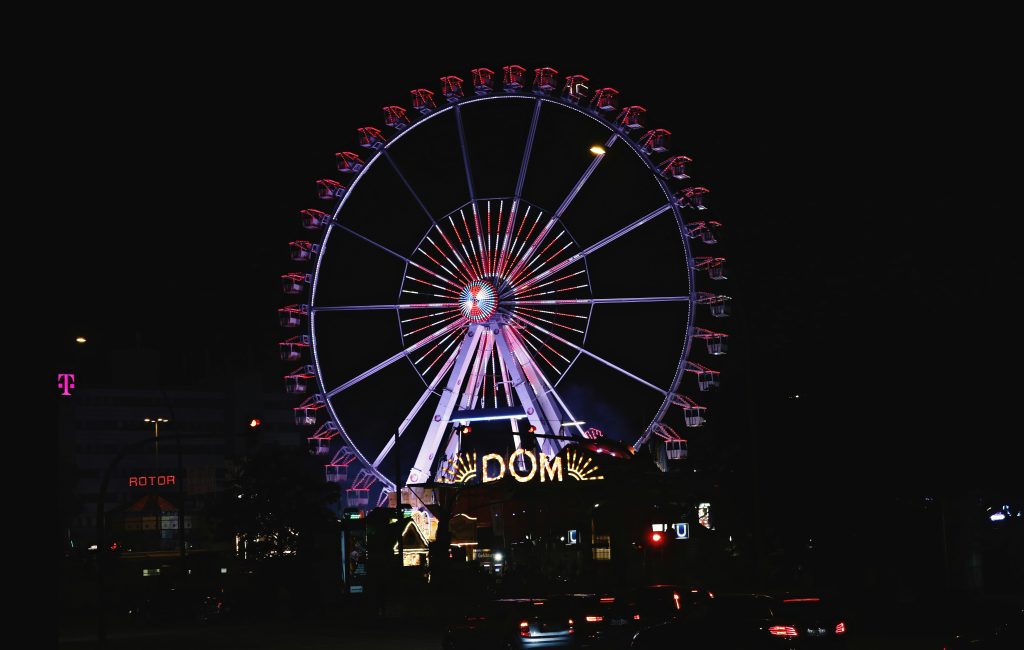 Hamburger DOM: beleuchtetes Riesenrad und das Eingangsschild des Hamburger DOM bei Nacht