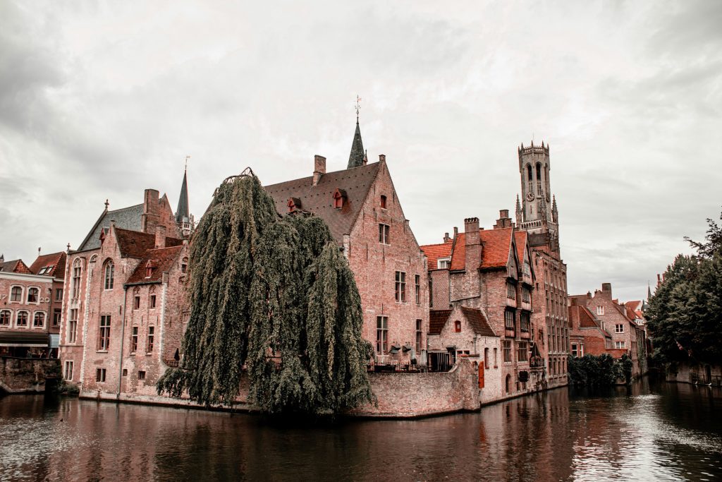 Bank holidays Belgium: scenic view of Bruges, Belgium, featuring historic brick buildings, a canal, and the Belfry tower in the background