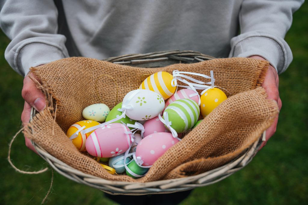 Bank holidays in Austria: Person holding a wicker basket lined with burlap, filled with pastel-colored decorated Easter eggs