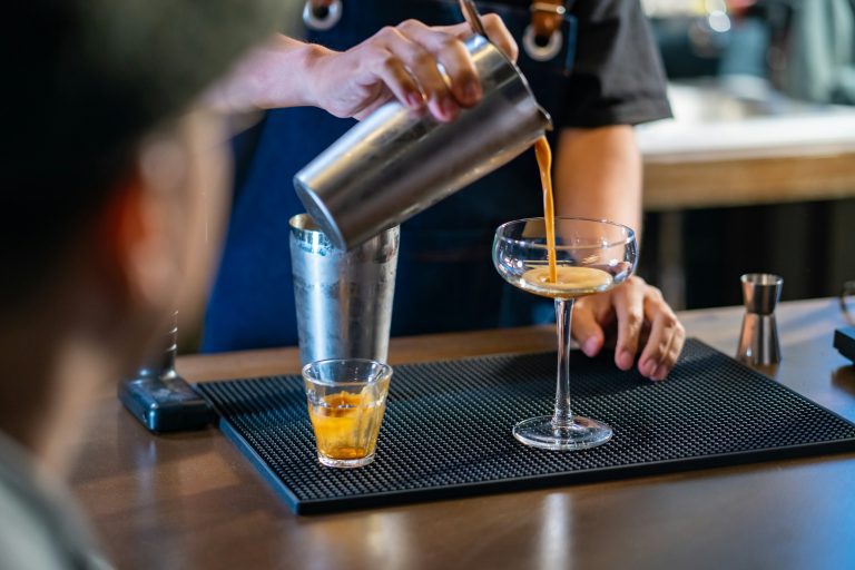 Bartender pouring an espresso martini into a coupe glass at a cocktail bar