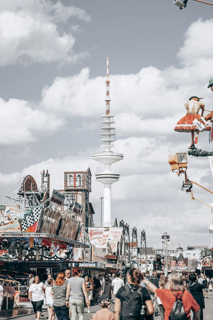 Hamburger DOM: Trubel auf dem Hamburger DOM in St. Pauli – mit Food-Ständen, Fahrgeschäften und dem Heinrich-Hertz-Turm unter einem teils bewölkten Himmel