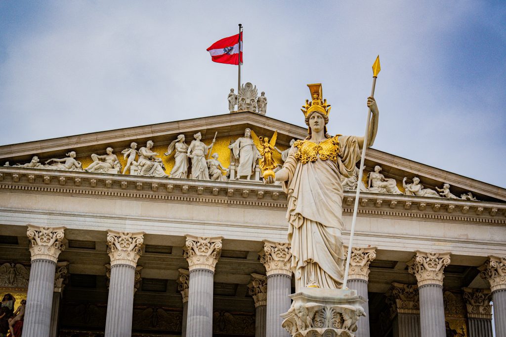 Bank holidays in Austria: Austrian Parliament Building in Vienna with the Pallas Athena Fountain and the Austrian flag waving above