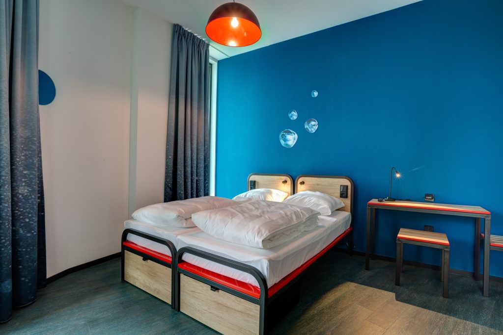 Double room with blue wall, red accents, desk and seating station