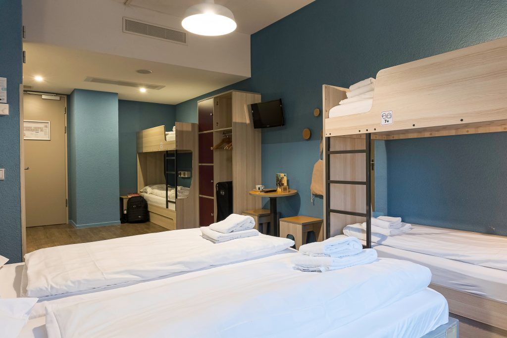 Room with two wooden bunk beds, two twin beds and light blue walls