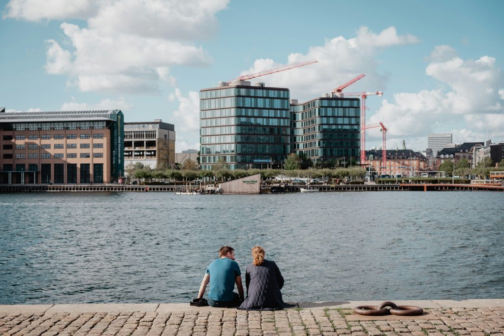 Denmark bank holidays: couple relaxing by the waterfront in Islands Brygge, Copenhagen, with city views
